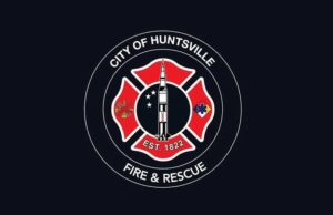 Huntsville aprueba terreno para nueva estación de bomberos Escudo oficial de Huntsville Fire and Rescue con la figura de un cohete espacial sobre fondo negro.