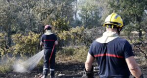 Incendios masivos en Francia arrasan miles de hectáreas Dos bomberos rociando agua sobre matorrales quemados durante los incendios en Francia.