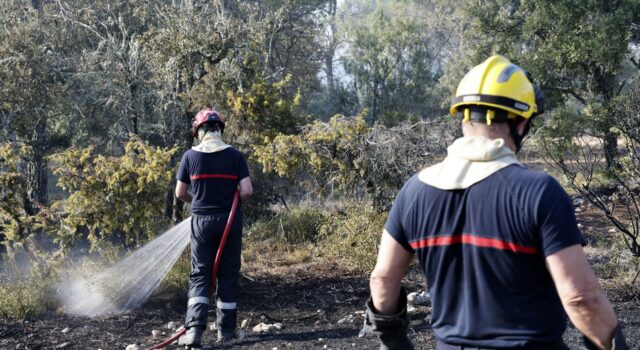 Incendios masivos en Francia arrasan miles de hectáreas Dos bomberos rociando agua sobre matorrales quemados durante los incendios en Francia.