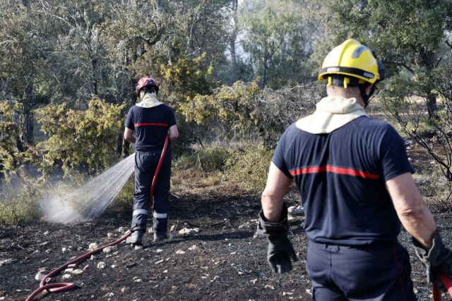 Incendios masivos en Francia arrasan miles de hectáreas Dos bomberos rociando agua sobre matorrales quemados durante los incendios en Francia.