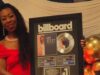 Kim Scott alcanza nuevo éxito número uno en Billboard La flautista Kim Scott sostiene un cuadro conmemorativo del número uno de Billboard por su canción Hide and Seek.