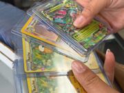 Alabama sufre ola de robos de valiosas cartas de Pokémon Manos sosteniendo cartas coleccionables de Pokémon en fundas protectoras como Raichu y Gengar en una tienda de Alabama.