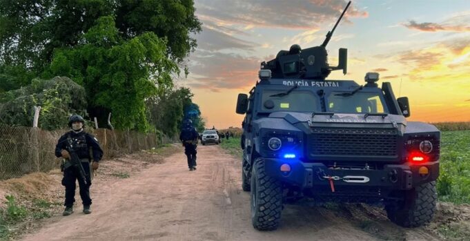 México confirma la muerte de 10 criminales en Sinaloa Vehículo blindado de la Policía Estatal y agentes armados resguardan un camino rural durante un operativo en México.