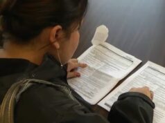 Permisos de trabajo para asilo protegidos por juez en EE. UU. Mujer revisando formularios impresos de solicitudes sobre una mesa para trámites de inmigración.