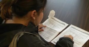 Permisos de trabajo para asilo protegidos por juez en EE. UU. Mujer revisando formularios impresos de solicitudes sobre una mesa para trámites de inmigración.