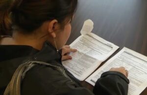 Permisos de trabajo para asilo protegidos por juez en EE. UU. Mujer revisando formularios impresos de solicitudes sobre una mesa para trámites de inmigración.