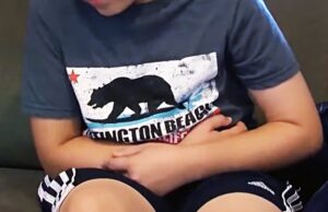 Alabama reporta 28 casos de Cyclospora en brote nacional Niño sentado en un sofá con expresión de dolor abdominal, indicando síntomas de ciclosporiosis.