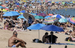 Ola de calor en Europa deja miles de muertos por temperaturas extremas Playa repleta de personas bajo sombrillas de colores para protegerse de la intensa ola de calor en Europa.
