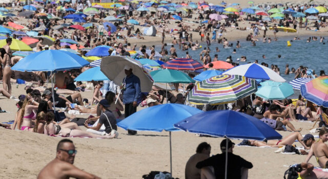 Ola de calor en Europa deja miles de muertos por temperaturas extremas Playa repleta de personas bajo sombrillas de colores para protegerse de la intensa ola de calor en Europa.