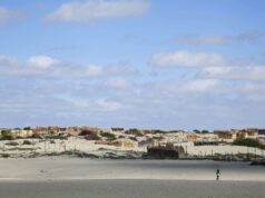 Piura registra temperaturas récord por El Niño Costero Persona camina por un terreno desértico de Piura con viviendas rústicas bajo un cielo despejado por El Niño Costero.