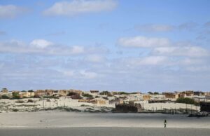 Piura registra temperaturas récord por El Niño Costero Persona camina por un terreno desértico de Piura con viviendas rústicas bajo un cielo despejado por El Niño Costero.