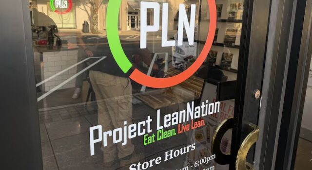 Project Lean Nation llega a Homewood con nutrición Fachada de Project Lean Nation en Homewood con su logotipo PLN y horarios de atención en la puerta de vidrio.