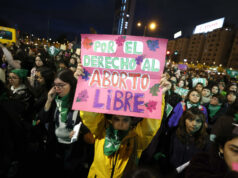 Protestas en Chile contra ley de latidos fetales y aborto Manifestante sostiene un cartel rosa sobre el aborto libre durante una marcha nocturna en Chile.