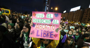 Protestas en Chile contra ley de latidos fetales y aborto Manifestante sostiene un cartel rosa sobre el aborto libre durante una marcha nocturna en Chile.