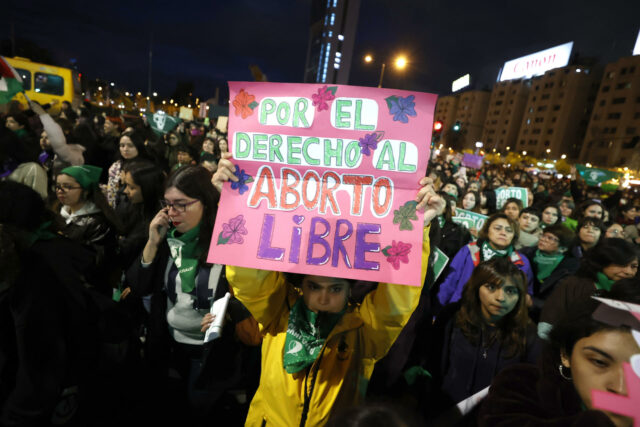 Cientos de chilenas rechazan el proyecto para escuchar el latido del feto antes de abortar Manifestante sostiene un cartel rosa sobre el aborto libre durante una marcha nocturna en Chile.
