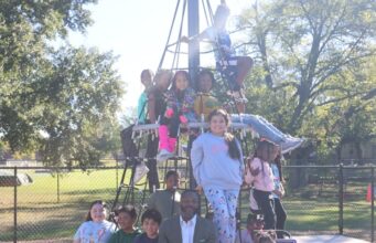 Birmingham aprueba presupuesto millonario enfocado en juventud El alcalde Randall L. Woodfin posa junto a un grupo de niños en una estructura de juego de un parque en Birmingham.