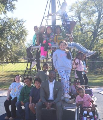 Birmingham aprueba presupuesto millonario enfocado en juventud El alcalde Randall L. Woodfin posa junto a un grupo de niños en una estructura de juego de un parque en Birmingham.