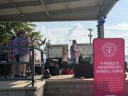 Renovación de City Lake Park en Russellville recibe impulso financiero Concierto en vivo "Jam on Sloss Lake" en el escenario de Russellville Alabama con cartel rosa de T-Mobile Hometown Grant.