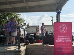 Renovación de City Lake Park en Russellville recibe impulso financiero Concierto en vivo "Jam on Sloss Lake" en el escenario de Russellville Alabama con cartel rosa de T-Mobile Hometown Grant.