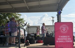 Renovación de City Lake Park en Russellville recibe impulso financiero Concierto en vivo "Jam on Sloss Lake" en el escenario de Russellville Alabama con cartel rosa de T-Mobile Hometown Grant.