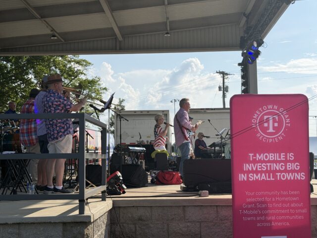 Concierto en vivo "Jam on Sloss Lake" en el escenario de Russellville Alabama con cartel rosa de T-Mobile Hometown Grant.