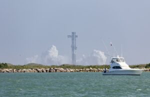 SpaceX cancela el lanzamiento número 13 de Starship Torre de lanzamiento de Starship rodeada de humo blanco con un yate navegando en primer plano en Texas.