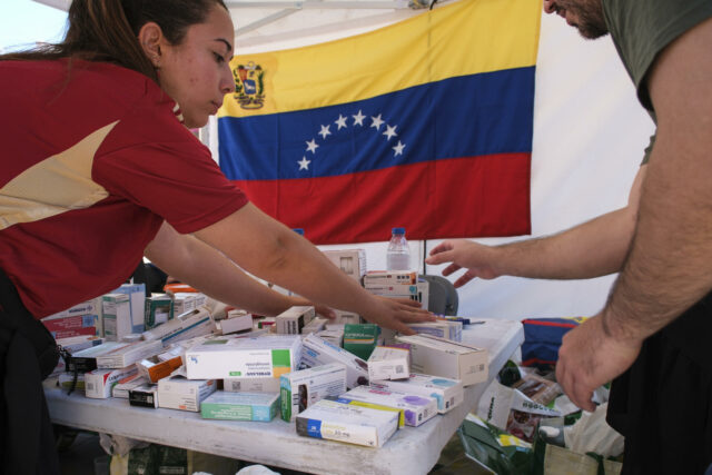 El Programa Mundial de Alimentos busca asistir a 500.000 personas en Venezuela tras sismos Personal de salud organiza cajas de medicamentos en una mesa con la bandera de Venezuela al fondo.