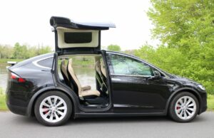 Precios de autos usados eléctricos suben en el mercado Tesla Model X negro con puertas Falcon desplegadas, auto usado eléctrico que encabeza la subida de precios.