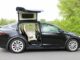 Precios de autos usados eléctricos suben en el mercado Tesla Model X negro con puertas Falcon desplegadas, auto usado eléctrico que encabeza la subida de precios.