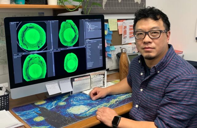 El investigador Tie Liu junto a una pantalla con escaneos verdes de hojas para detectar estrés hídrico.