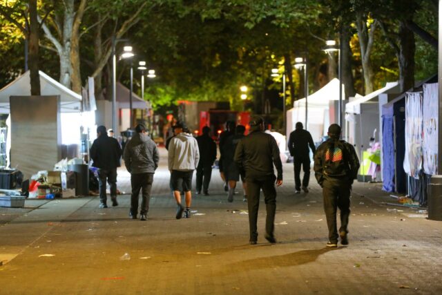 Personas caminando por la zona del tiroteo en Seattle Center rodeada de carpas nocturnas.