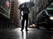 Tormentas severas en Nueva York amenazan con tornados Hombre con paraguas bajo fuertes lluvias y tormentas severas en una calle inundada de Nueva York.