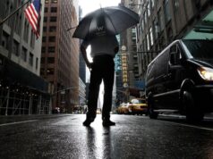 Tormentas severas en Nueva York amenazan con tornados Hombre con paraguas bajo fuertes lluvias y tormentas severas en una calle inundada de Nueva York.