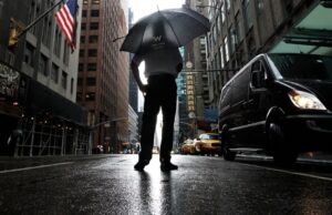 Tormentas severas en Nueva York amenazan con tornados Hombre con paraguas bajo fuertes lluvias y tormentas severas en una calle inundada de Nueva York.