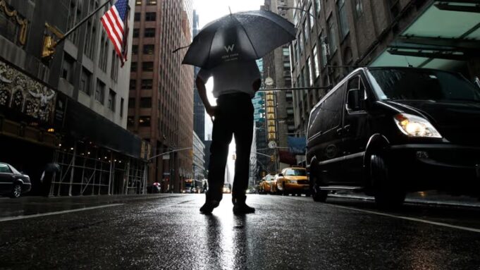 Tormentas severas en Nueva York amenazan con tornados Hombre con paraguas bajo fuertes lluvias y tormentas severas en una calle inundada de Nueva York.