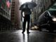 Tormentas severas en Nueva York amenazan con tornados Hombre con paraguas bajo fuertes lluvias y tormentas severas en una calle inundada de Nueva York.