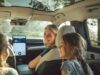 Vehículos eléctricos tendrán pruebas de manejo gratis Una madre sonríe a sus hijas desde el asiento delantero de un moderno vehículo eléctrico con techo panorámico de cristal.