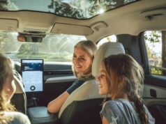 Vehículos eléctricos tendrán pruebas de manejo gratis Una madre sonríe a sus hijas desde el asiento delantero de un moderno vehículo eléctrico con techo panorámico de cristal.