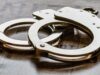 Arresto en Alabama de alumno por amenaza terrorista escolar Esposas metálicas de policía sobre una superficie de madera tras el arresto de un estudiante en Alabama.