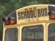 Escasez de conductores causa retrasos en autobuses escolares Parte trasera superior de un autobús escolar amarillo con las letras School Bus y luces de advertencia.