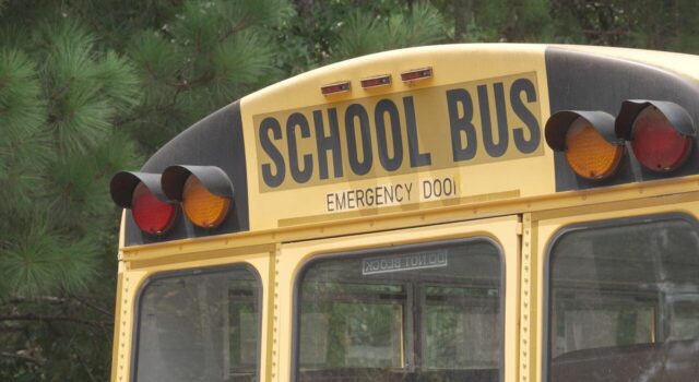 Escasez de conductores causa retrasos en autobuses escolares Parte trasera superior de un autobús escolar amarillo con las letras School Bus y luces de advertencia.