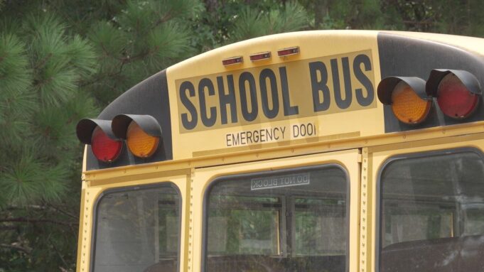 Escasez de conductores causa retrasos en autobuses escolares Parte trasera superior de un autobús escolar amarillo con las letras School Bus y luces de advertencia.