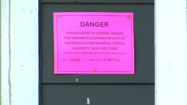 Letrero rosa de advertencia que declara un edificio inhabitable por bomberos de Homewood, Alabama.