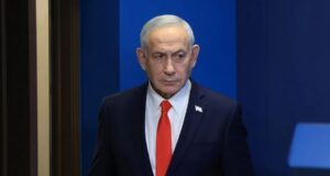 Netanyahu denuncia un complot iraní para matar a su hijo Benjamín Netanyahu con traje oscuro y corbata roja en un acto oficial tras denunciar complot de Irán.