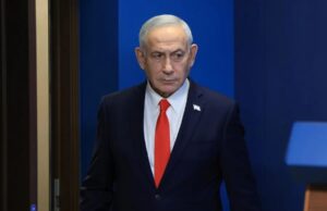 Netanyahu denuncia un complot iraní para matar a su hijo Benjamín Netanyahu con traje oscuro y corbata roja en un acto oficial tras denunciar complot de Irán.