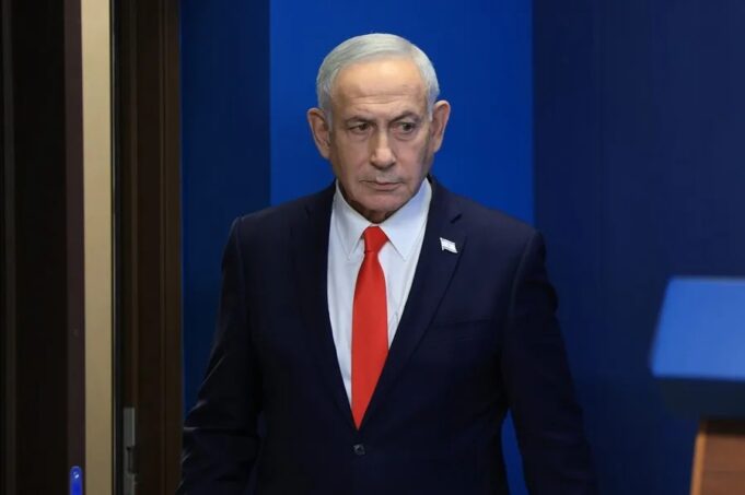 Netanyahu denuncia un complot iraní para matar a su hijo Benjamín Netanyahu con traje oscuro y corbata roja en un acto oficial tras denunciar complot de Irán.