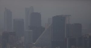 Contaminación atmosférica agrava la artritis reumatoide Vista panorámica de edificios urbanos cubiertos por una densa capa de contaminación atmosférica y smog.