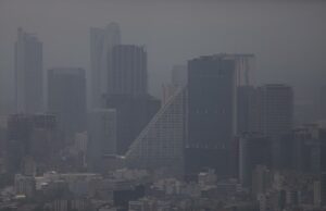 Contaminación atmosférica agrava la artritis reumatoide Vista panorámica de edificios urbanos cubiertos por una densa capa de contaminación atmosférica y smog.