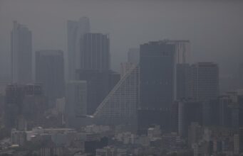 Contaminación atmosférica agrava la artritis reumatoide Vista panorámica de edificios urbanos cubiertos por una densa capa de contaminación atmosférica y smog.