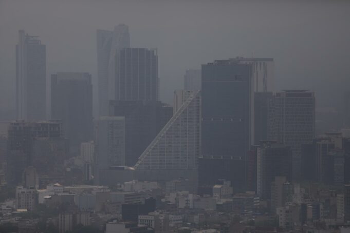Contaminación atmosférica agrava la artritis reumatoide Vista panorámica de edificios urbanos cubiertos por una densa capa de contaminación atmosférica y smog.